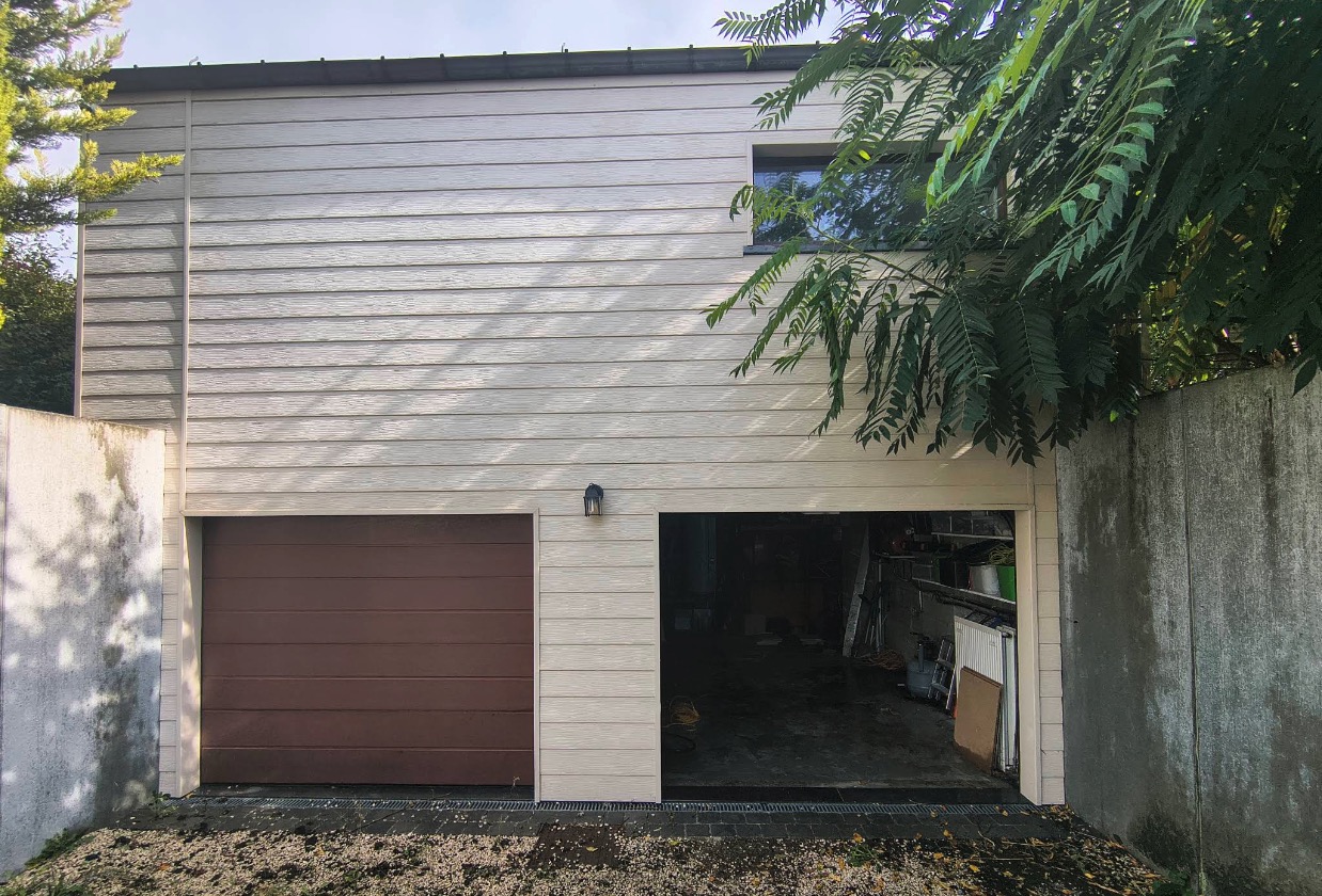 Façade en bardage clair avec porte de garage brune